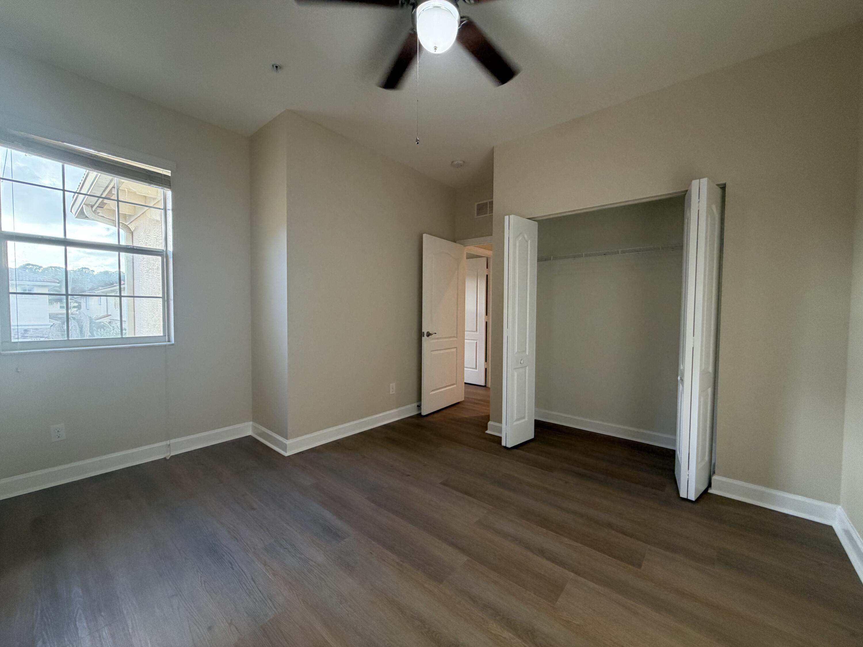 9491 Southwest Merlin Court Stuart, FL 34997 - Photo 19 of 45 a view of an empty room with wooden floor and window