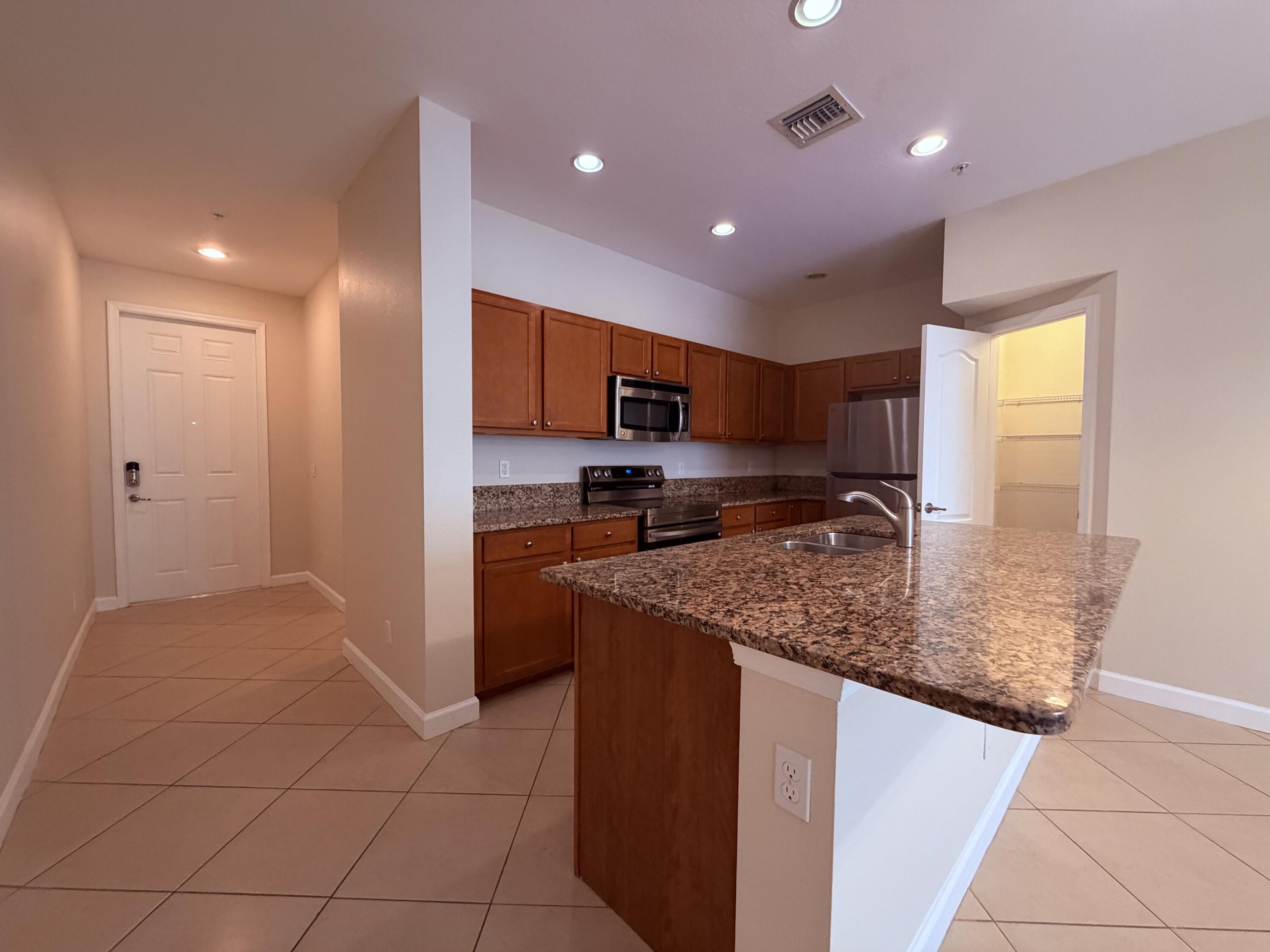 9491 Southwest Merlin Court Stuart, FL 34997 - Photo 9 of 45 a kitchen with stainless steel appliances granite countertop a sink and a stove