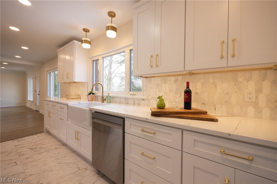 32887 Cedar Road Mayfield Heights, OH 44124 - Photo 7 of 44 Kitchen with white cabinetry, backsplash, decorative light fixtures, and stainless steel dishwasher