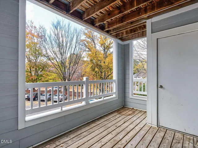 a porch with wooden floor next to a yard