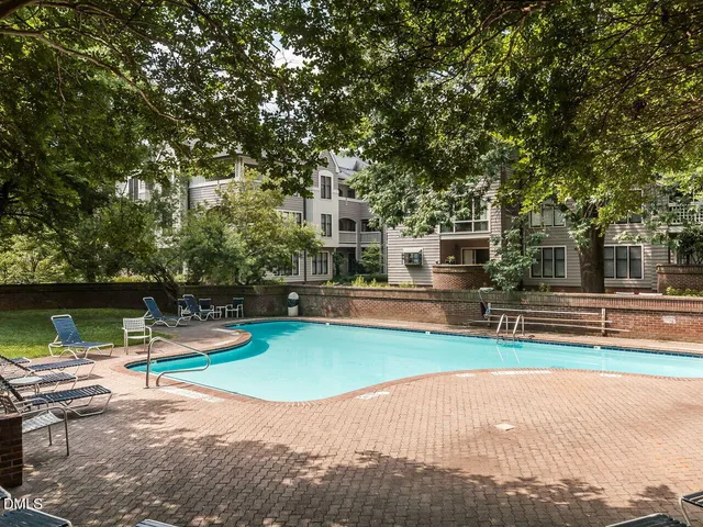 a front view of a building with lot of cars and trees