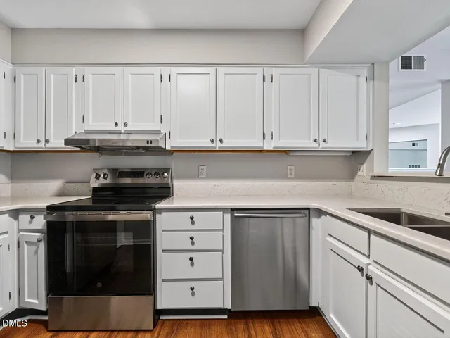 a kitchen with stainless steel appliances granite countertop a refrigerator stove a sink and white cabinets