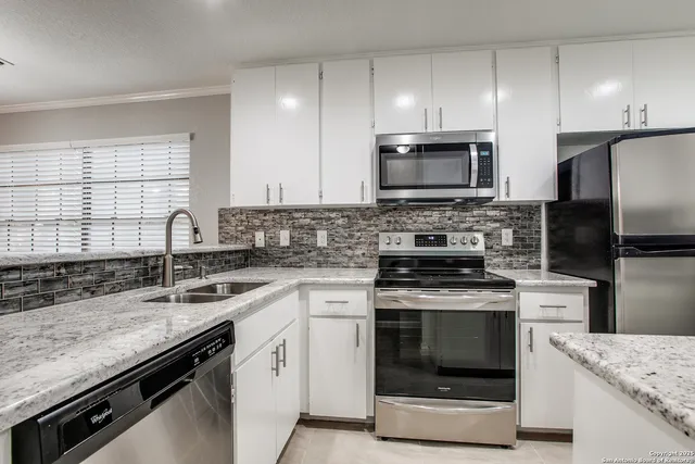 a kitchen with granite countertop a stove sink and refrigerator