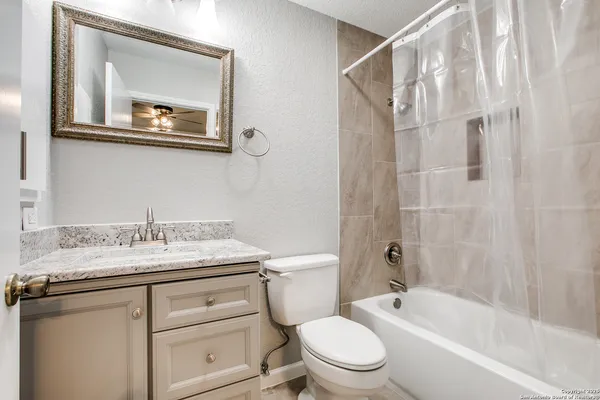 a bathroom with a granite countertop sink toilet a mirror and shower