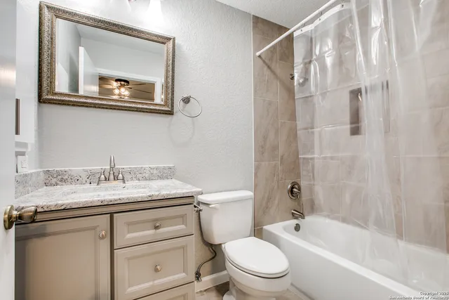 a bathroom with a granite countertop sink toilet a mirror and shower