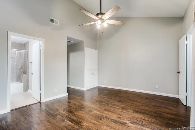 an empty room with wooden floor and a ceiling fan
