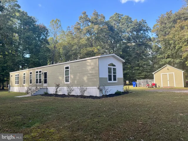 a front view of house with yard and trees in the background
