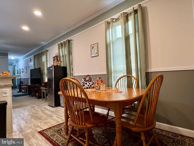 a kitchen with stainless steel appliances granite countertop a refrigerator a stove a sink a dining table and chairs with wooden floor