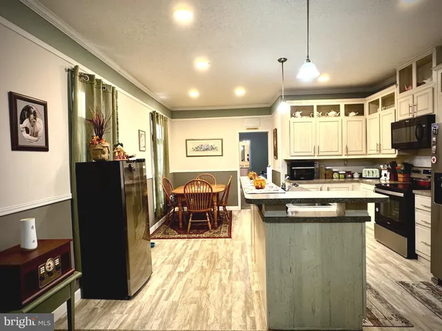 a living room with stainless steel appliances furniture and kitchen view