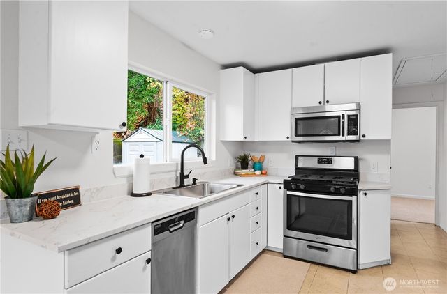 a kitchen with appliances a sink a window and cabinets