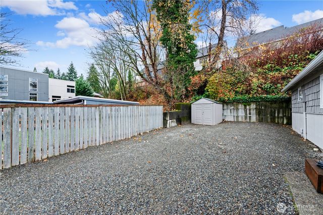 a view of a house with a large tree and wooden fence