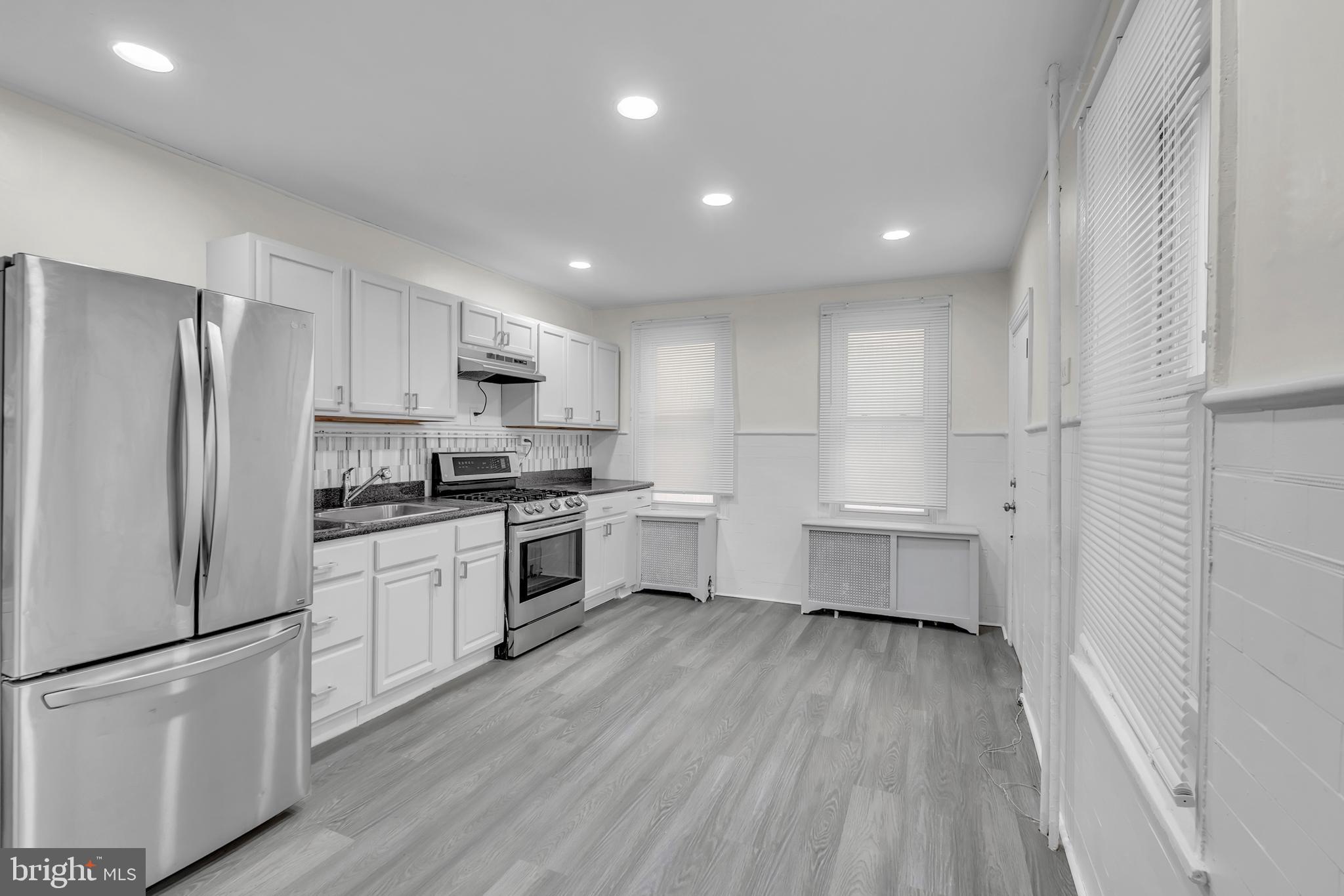 1419 Ellsworth Street Philadelphia, PA 19146 - Photo 7 of 17 a kitchen with white cabinets and stainless steel appliances