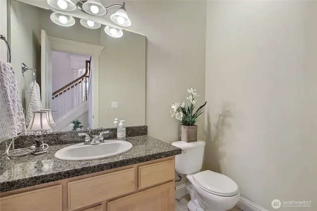 a bathroom with a granite countertop toilet sink and mirror