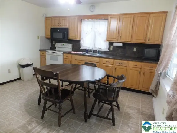 a kitchen with stainless steel appliances granite countertop a table chairs sink and cabinets
