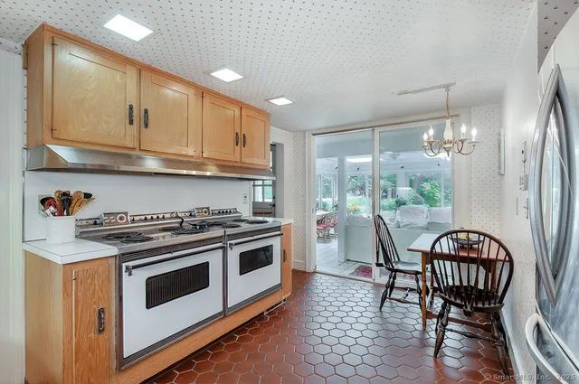 a kitchen with stainless steel appliances granite countertop a stove a refrigerator a kitchen island with a dining table and chairs