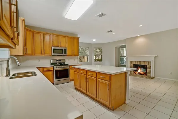a kitchen with kitchen island granite countertop a stove top oven a sink a counter top space and cabinets