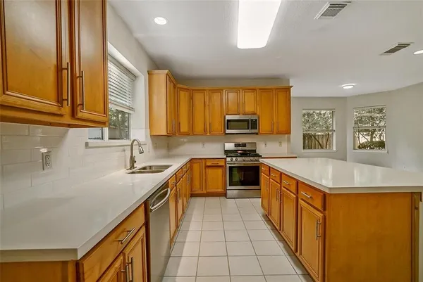 a kitchen with stainless steel appliances granite countertop a sink counter space cabinets a stove and a window