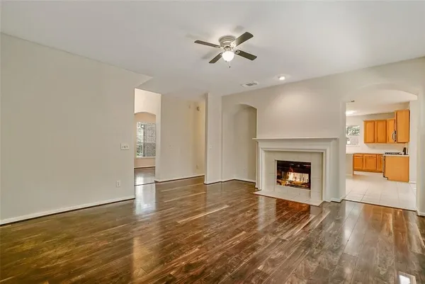 an empty room with wooden floor fireplace and windows