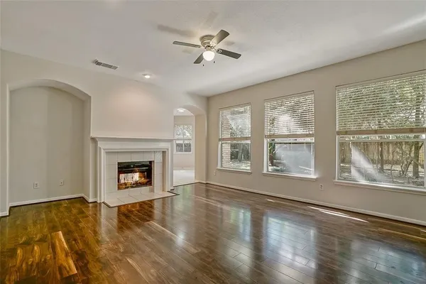 an empty room with windows fireplace and wooden floor