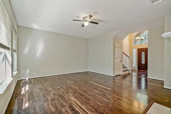 an empty room with wooden floor fan and windows