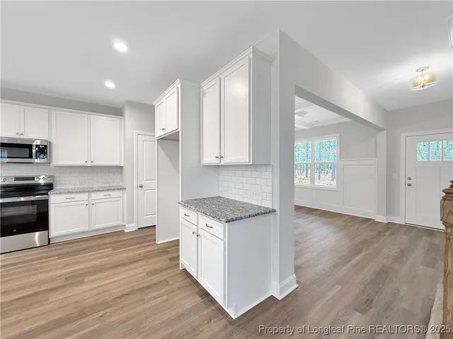 a large kitchen with cabinets wooden floor and stainless steel appliances