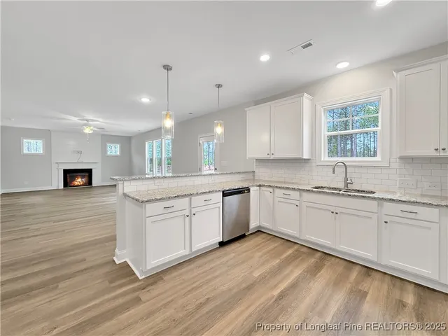 a kitchen with stainless steel appliances granite countertop a stove top oven a sink dishwasher and a refrigerator with wooden floor