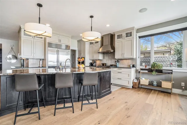 a kitchen with stainless steel appliances granite countertop a stove a sink dishwasher a dining table and chairs with wooden floor