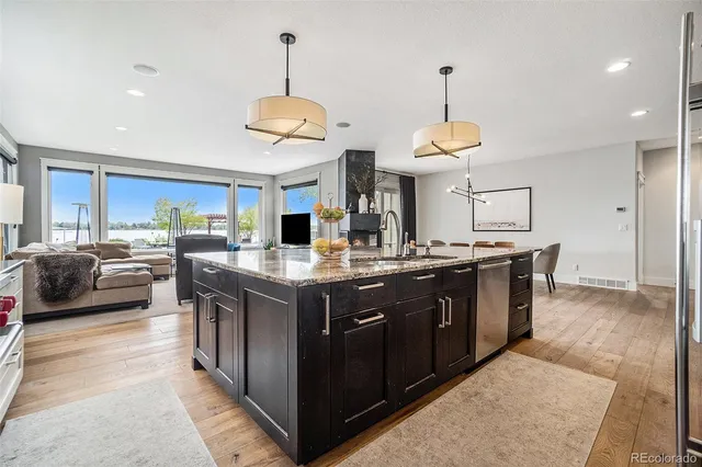 a kitchen with stainless steel appliances granite countertop a sink a stove and a wooden floors