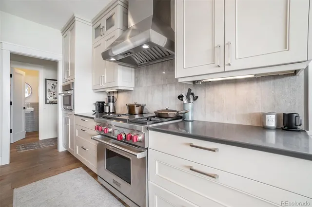 a kitchen with stainless steel appliances granite countertop a stove and a white cabinets