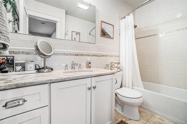 a bathroom with a granite countertop sink toilet mirror vanity and shower