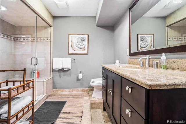a spacious bathroom with a granite countertop sink a toilet a mirror and shower