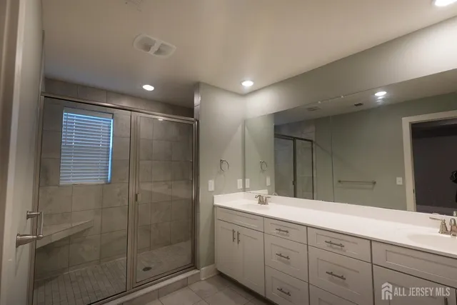 a spacious bathroom with a double vanity sink and mirror with shower