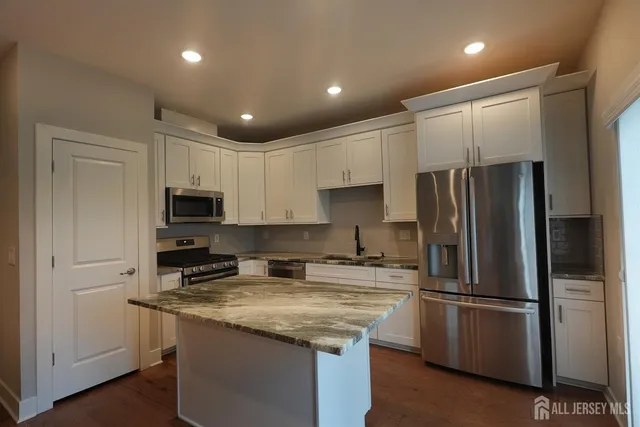 a kitchen with stainless steel appliances granite countertop a refrigerator a stove a sink and a microwave