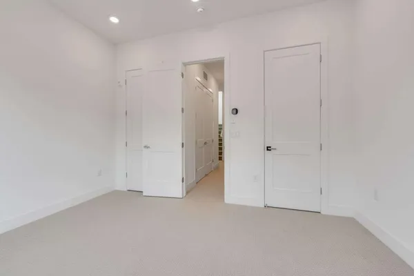 an empty room with white cabinet and mirrors