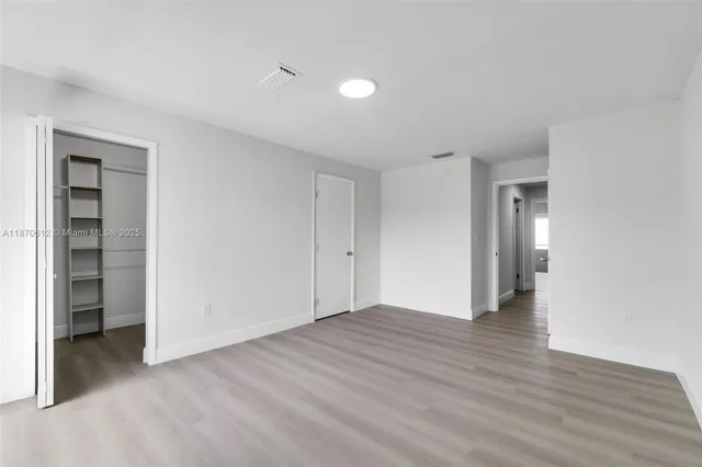 a view of an empty room with wooden floor and closet