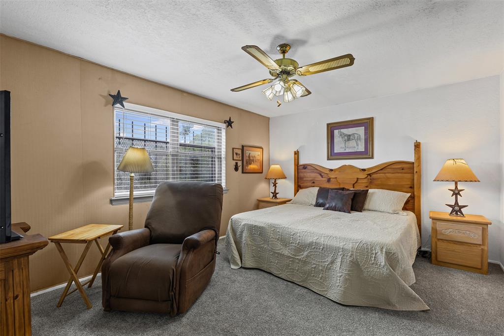2900 Peel Road Springtown, TX 76082 - Photo 13 of 34 a spacious bedroom with a bed a couch and a chandelier