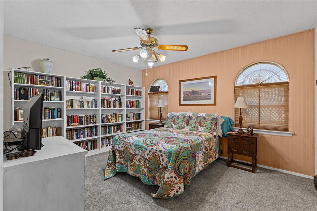 2900 Peel Road Springtown, TX 76082 - Photo 15 of 34 a bedroom with a bed a book shelf and a chandelier