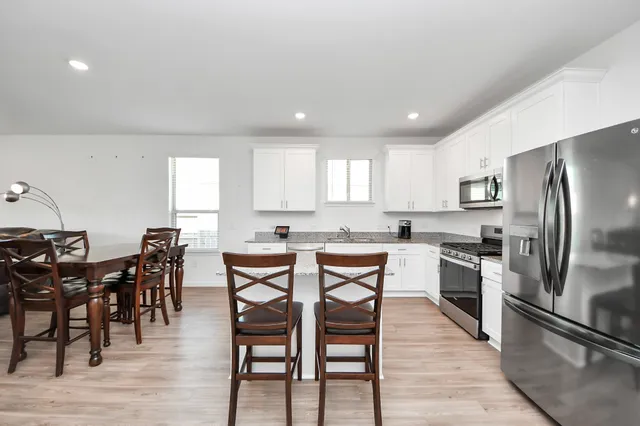 a kitchen with stainless steel appliances granite countertop a dining table chairs stove refrigerator and cabinets
