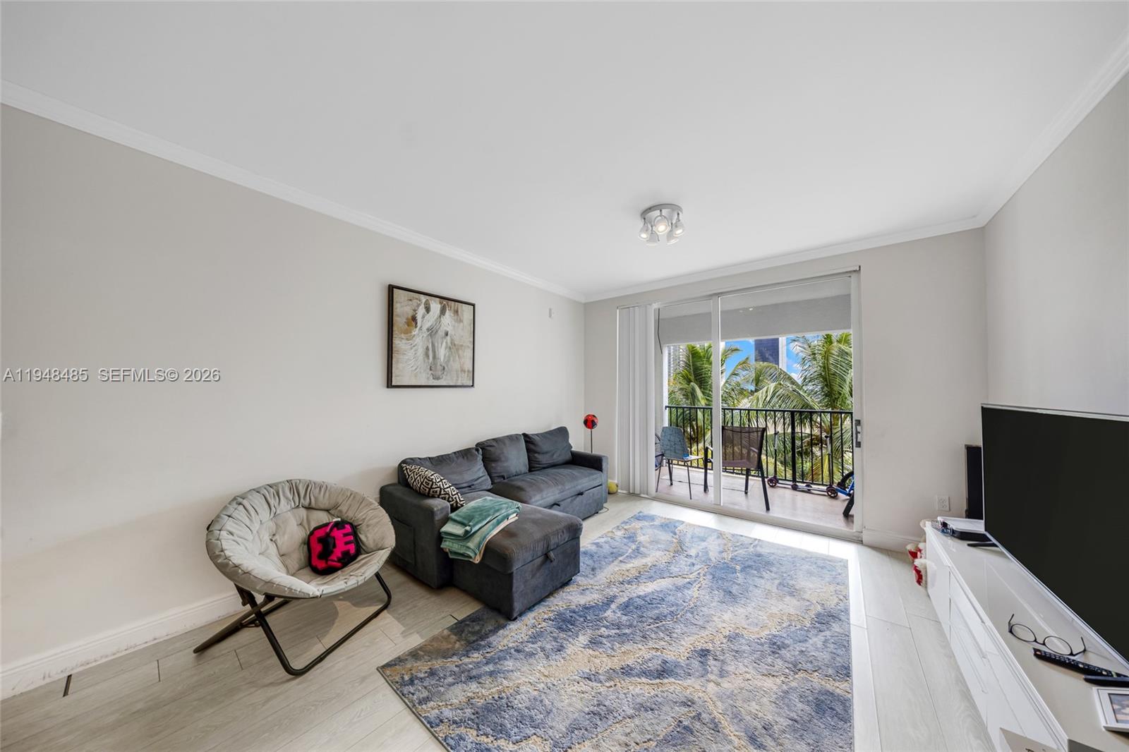 17145 North Bay Road, Unit 4506 Sunny Isles Beach, FL 33160 - Photo 1 of 10 a living room with furniture a flat screen tv and a floor to ceiling window