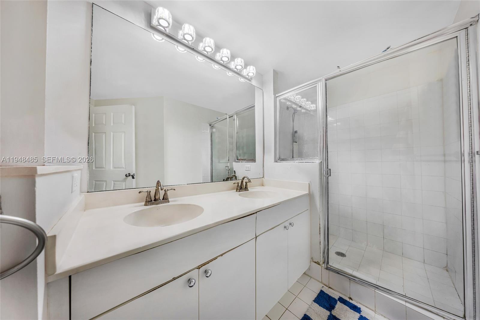 17145 North Bay Road, Unit 4506 Sunny Isles Beach, FL 33160 - Photo 10 of 10 a bathroom with a double vanity sink mirror and shower