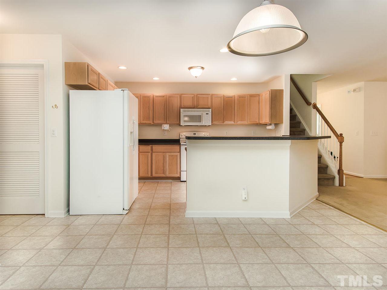 4720 Drewbridge Way Raleigh, NC 27604 - Photo 10 of 21 a kitchen with kitchen island granite countertop a stove a sink and a refrigerator