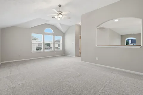 an empty room with windows and chandelier fan