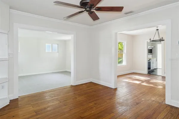 a view of empty room with wooden floor and ceiling fan