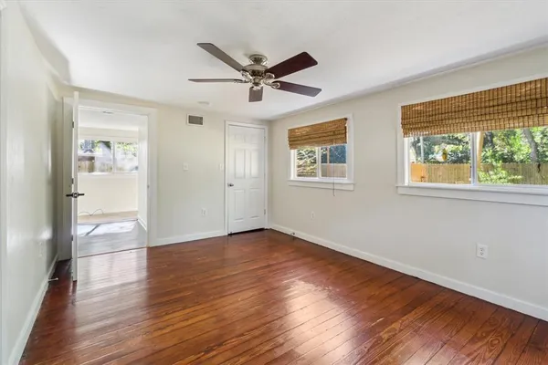 a view of empty room with wooden floor and fan