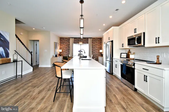 a open kitchen with stainless steel appliances kitchen island granite countertop a stove top oven a sink dishwasher a dining table and chairs with wooden floor