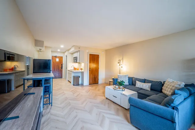a living room with furniture a flat screen tv and kitchen view