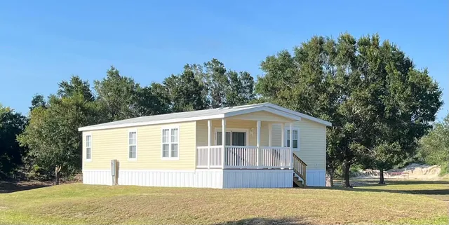 a front view of house with yard and trees in the background