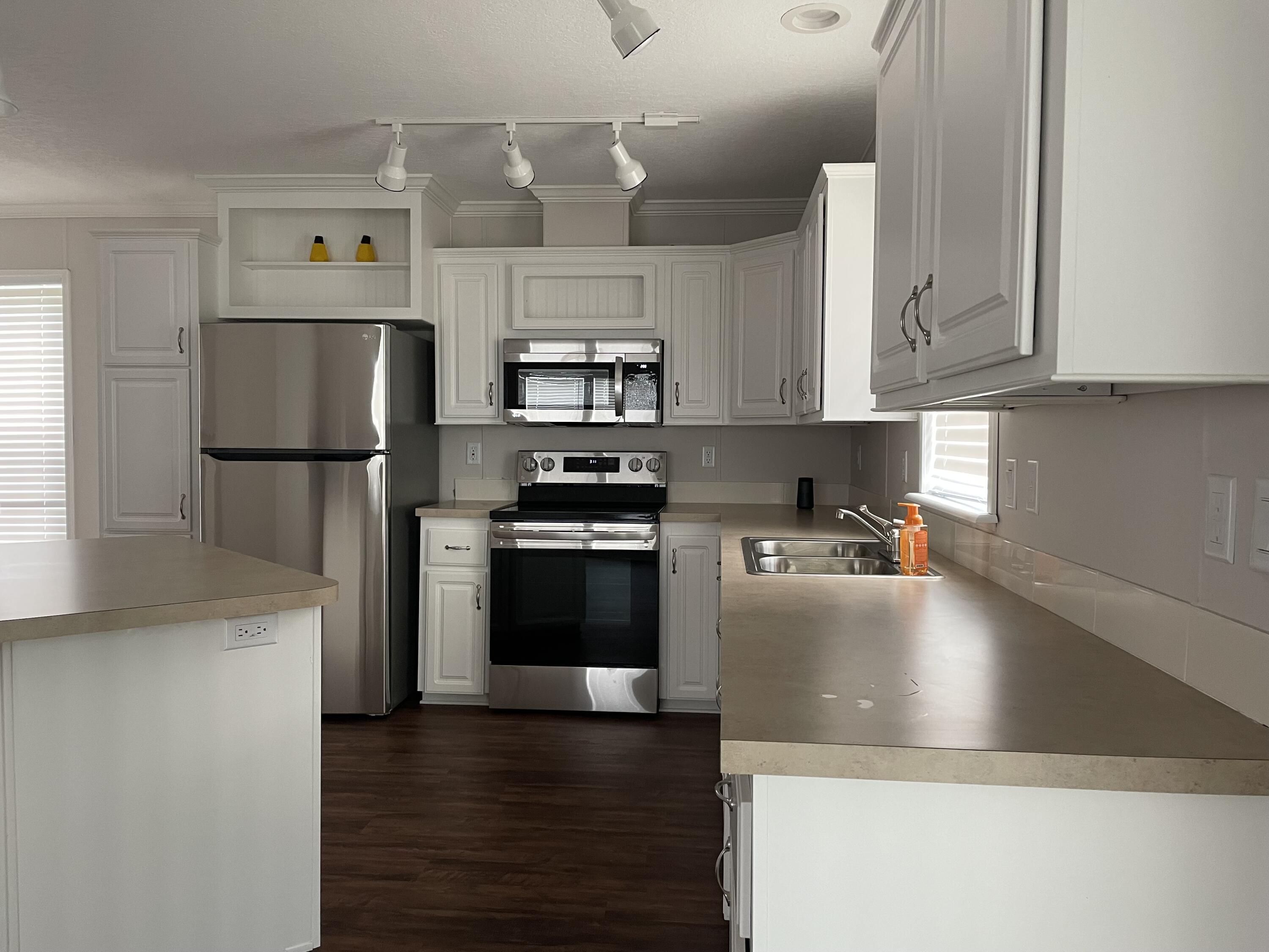 18459 260th Street Okeechobee, FL 34972 - Photo 7 of 15 a kitchen with stainless steel appliances a refrigerator a stove a sink and white cabinets