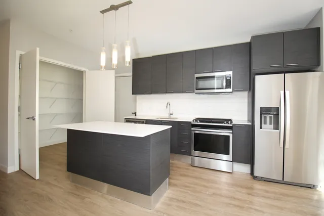 a kitchen with stainless steel appliances kitchen island granite countertop a refrigerator and a stove top oven