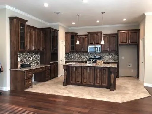 a kitchen with stainless steel appliances kitchen island granite countertop a stove refrigerator and cabinets